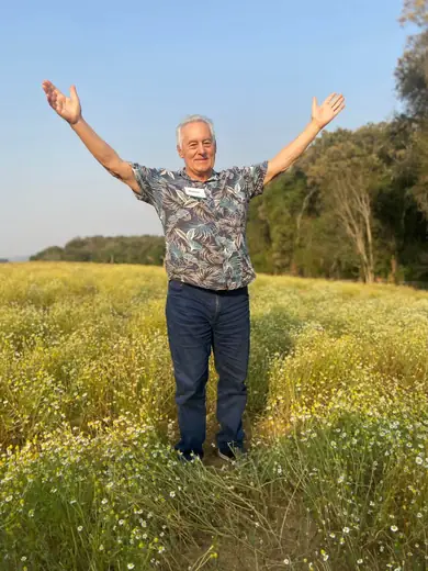 Senhor de braços abertos em um campo florido durante passeio ao ar livre
